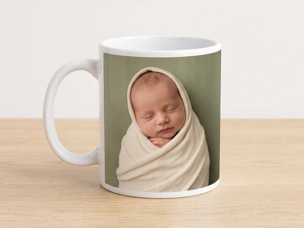 Photo mug printed with a newborn wrapped in cream against sage green