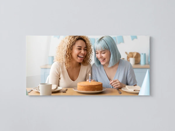 Panoramic acrylic print of two friends laughing over a birthday cake with one candle