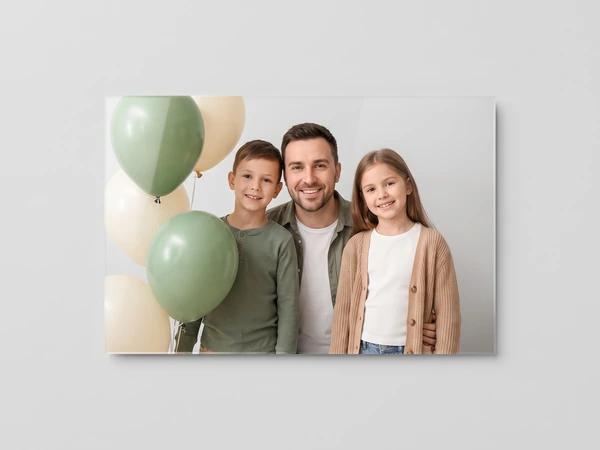 Acrylic print of a father and two children standing by green and cream balloons