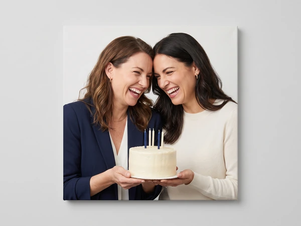 Canvas print of two laughing women holding a cake with lit candles