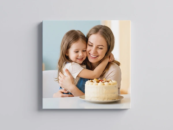 Canvas print of a little girl hugging her mother beside a birthday cake