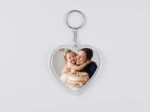 Heart keychain on a chain with a photo of a mother and daughter behind a birthday cake