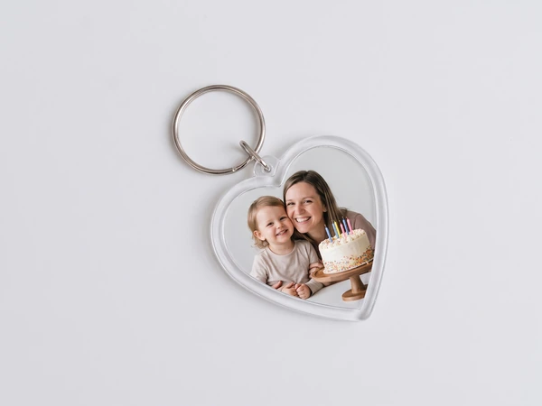 Heart keychain lying flat with a photo of a mother and toddler beside a cake with candles