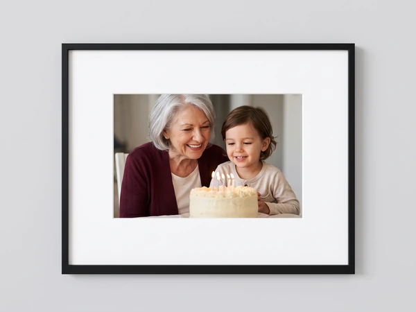 Black framed print of a grandmother and granddaughter blowing out birthday candles