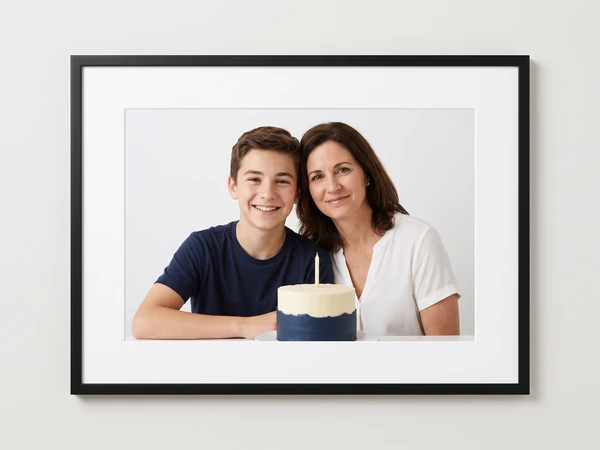Black framed print of a teenage boy and his mother with a navy and white cake