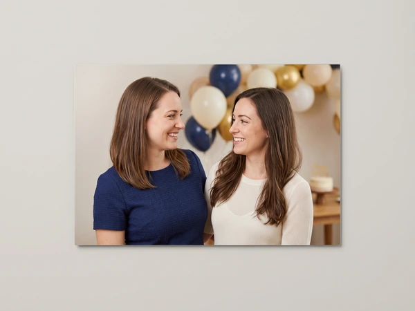 Metal print of two sisters in front of navy, gold and cream balloons