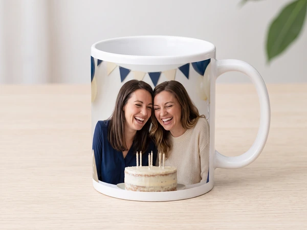 Classic photo mug printed with two women laughing over a candle cake under bunting