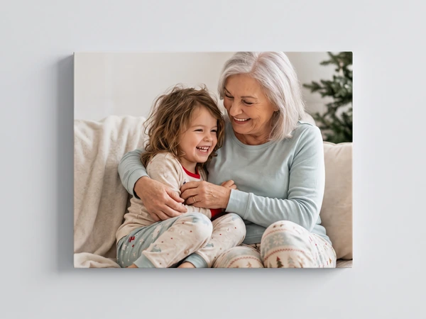 Canvas print of a grandmother hugging a little girl in pajamas on a sofa