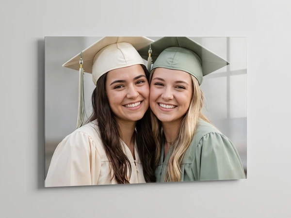 Acrylic print of two graduates in cream and sage caps cheek to cheek