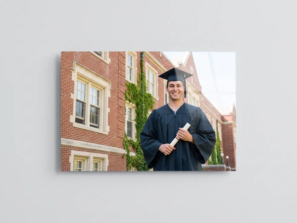 Acrylic print of a graduate with a rolled diploma in front of an ivy-covered brick hall
