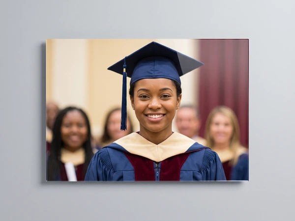 Acrylic print of a smiling graduate in a navy cap and gold hood at a ceremony