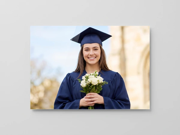 Acrylic print of a graduate in a navy gown holding a bouquet of white roses