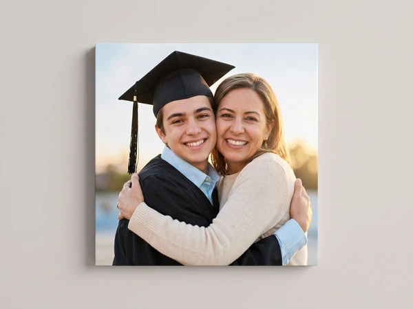 Canvas print of a graduate in a black cap hugging his mother
