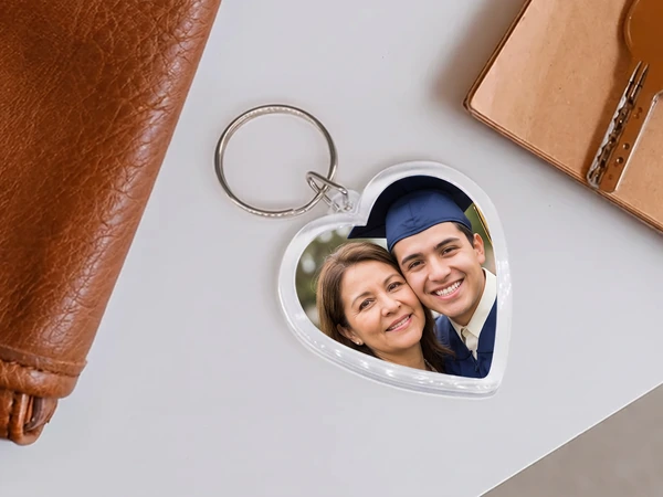 Heart keychain beside a leather wallet with a photo of a graduate and his mother