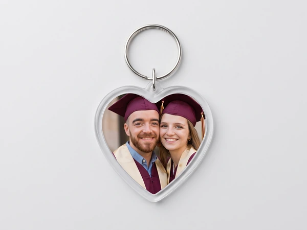 Heart keychain with a photo of two graduates in maroon caps cheek to cheek