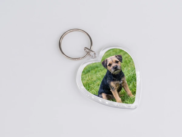 Heart keychain lying flat with a photo of a terrier puppy sitting in grass