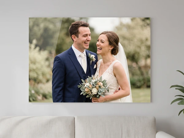 Acrylic print of a laughing bride and groom with a bouquet, hung above a sofa