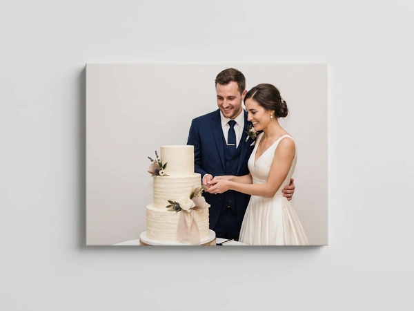 Canvas print of a bride and groom cutting a three-tier white wedding cake