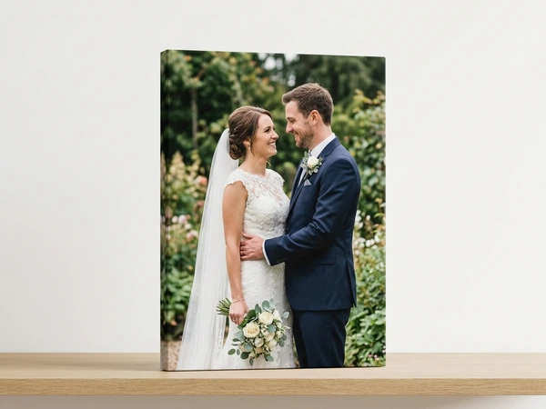 Portrait canvas print of a bride and groom in a garden, standing on a wooden shelf