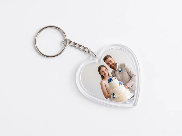 Heart keychain on a chain with a photo of a couple beside a tiered wedding cake
