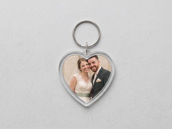 Heart keychain on a speckled surface with a photo of a bride and groom in gray