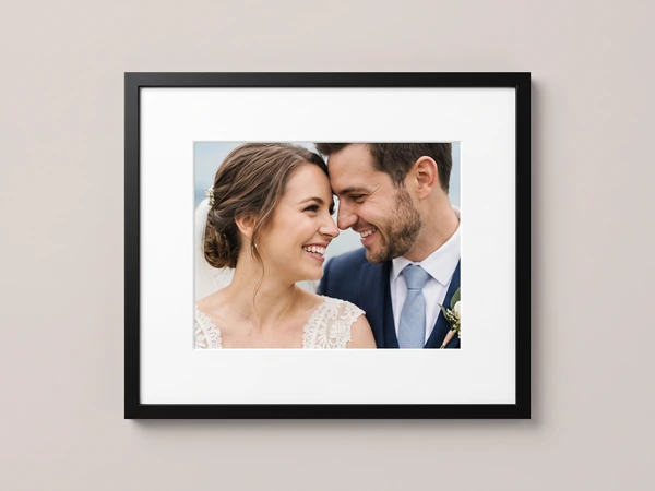 Black framed close-up print of a bride and groom smiling forehead to forehead