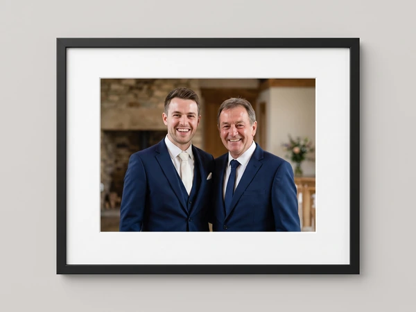 Black framed print of a groom and his father in navy suits