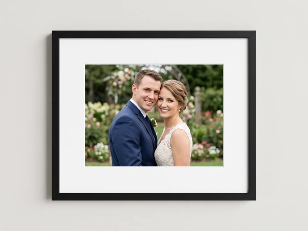 Black framed print of a bride and groom smiling in a rose garden