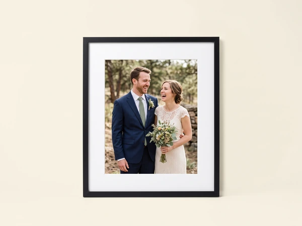 Black framed print of a laughing couple, the bride holding greenery