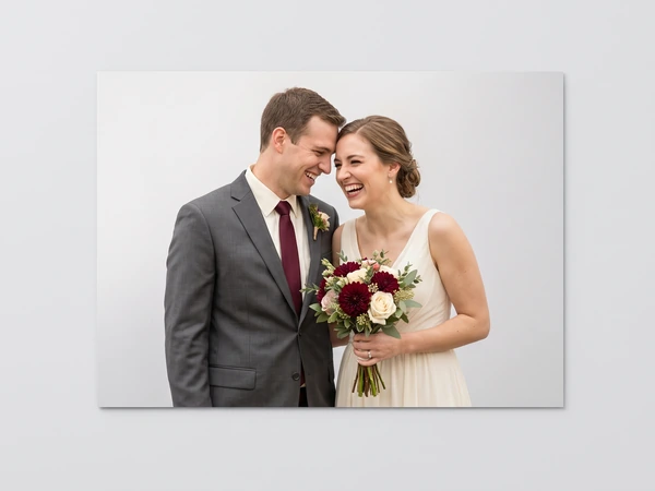 Metal print of a bride holding red and white roses laughing with her groom