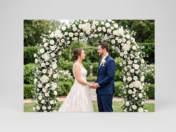 Metal print of a bride and groom holding hands under a white rose arch