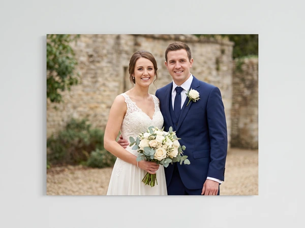 Metal print of a bride and groom in front of an old stone wall