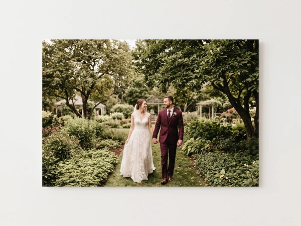 Metal print of a couple walking through a shady garden, the groom in burgundy