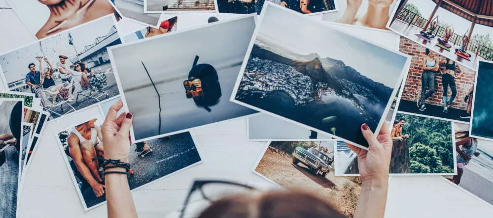 How to Resize an Image. Person holding two photo prints above more scattered prints.