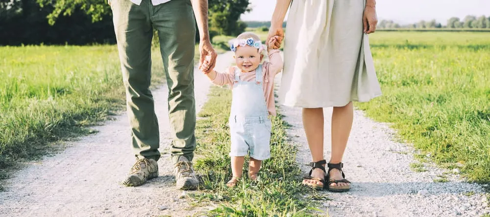 Wall Art for Nursery: Tips from Our Decor Experts. Smiling baby walking with parents. 