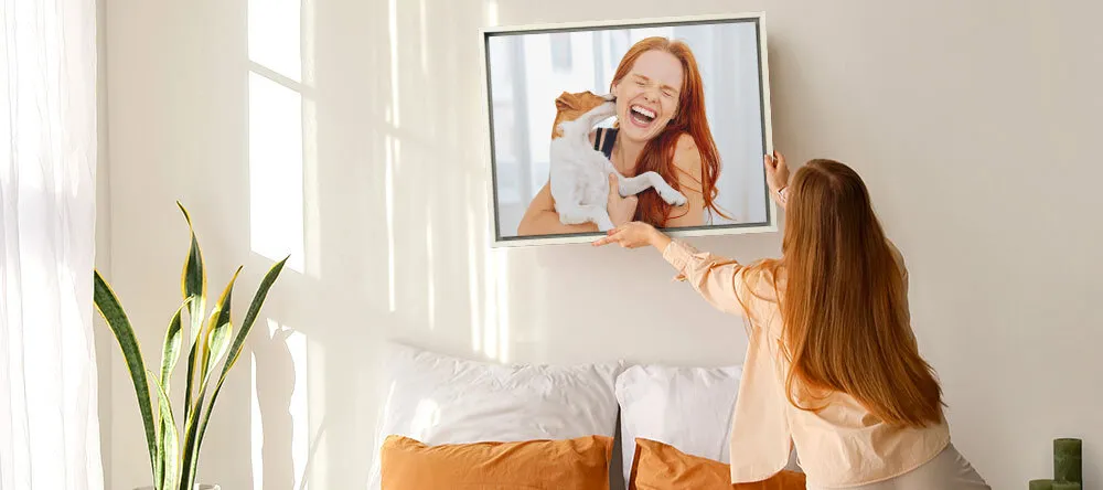 What is a Floating Frame for Canvas? Woman hanging framed print on wall.