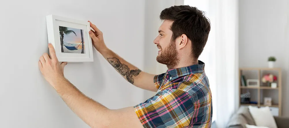 a person attaching a magnetized frame to a wall