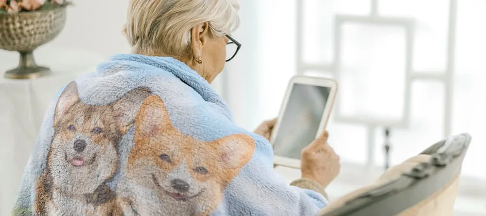 Personalized blankets for grandma: a lady wrapped in a printed blanket is browsing her tablet