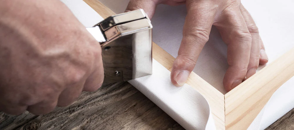 Is canvas waterproof: a person manually stretching canvas on a frame