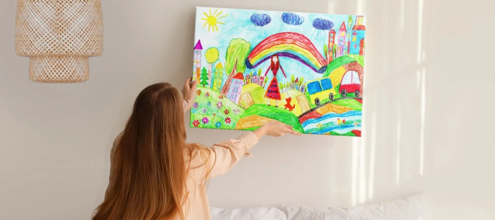 mother hanging up canvas print of child’s drawing