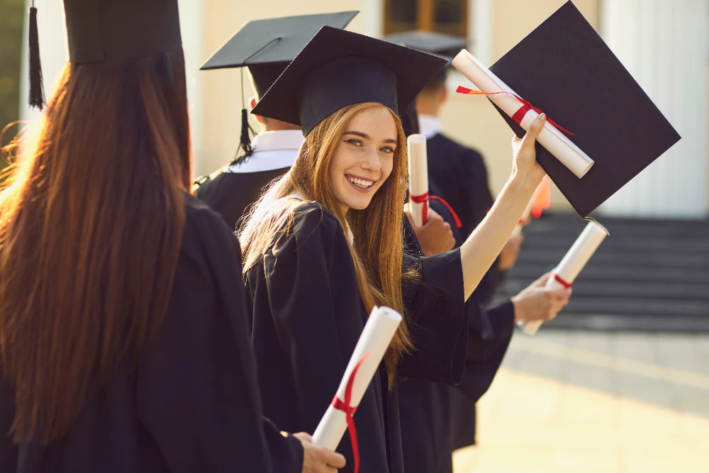 An open book with a graduation cap and diploma on a stack of books, representing learning and achievement