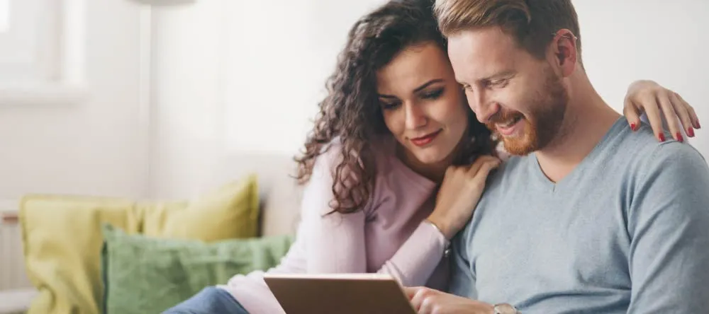 Custom-Made Canvases: 10 Myths Debunked. Young couple looking for canvas prints online on tablet.