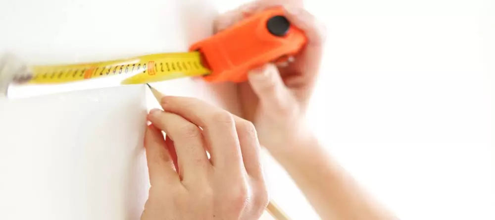 How to Hang a Poster: a man measuring the wall space with an eye level