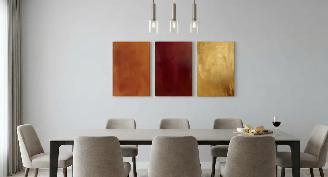 Three abstract canvas prints in warm tones displayed above a contemporary dining room table