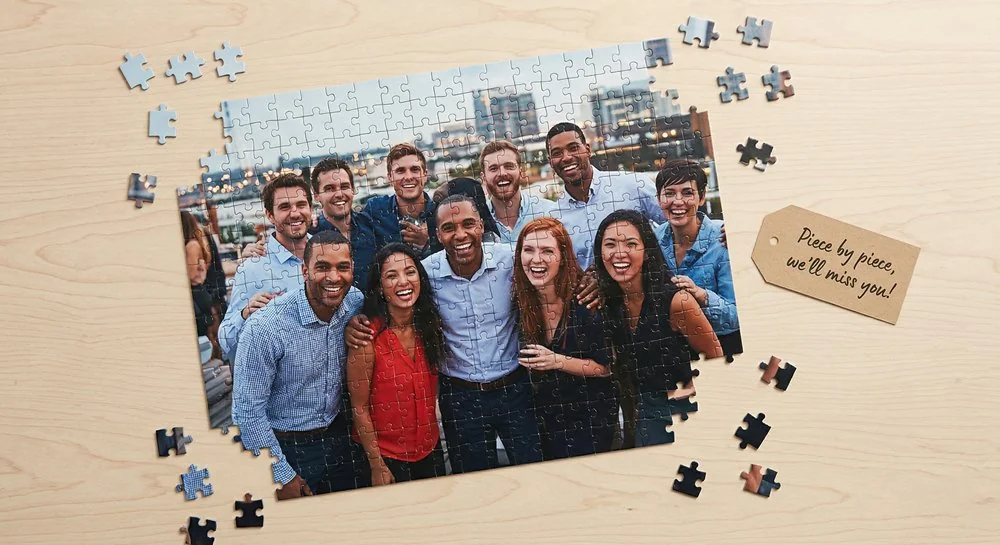 Personalized photo puzzle gift for going away coworker showing a team group photo being assembled on a wooden table