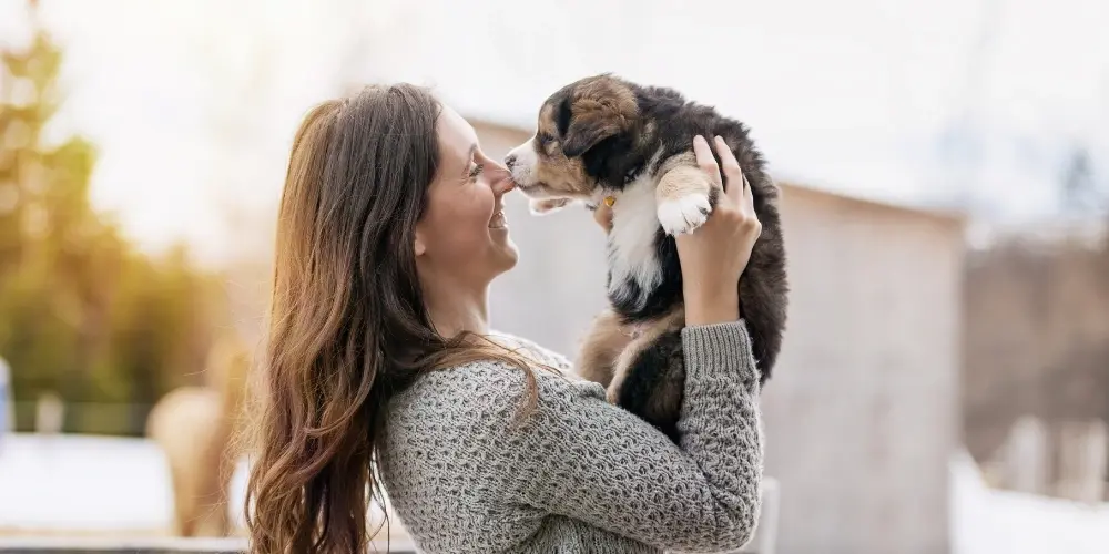 Happy dog owner holding puppy outdoors on National Puppy Day