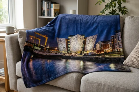 photo blanket belfast – a plush blanket printed edge to edge with the Titanic Quarter at night draped over a sofa