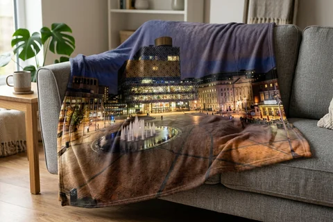 photo blanket birmingham – a plush blanket printed edge to edge with Centenary Square at night draped over a sofa