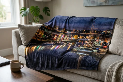 photo blanket bristol – a plush blanket printed edge to edge with the Harbourside at night draped over a sofa