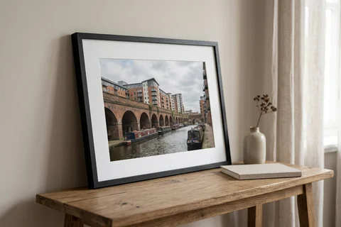 framed photo print leeds – a framed print of Granary Wharf and the canal with a white mount and black frame standing on a console table